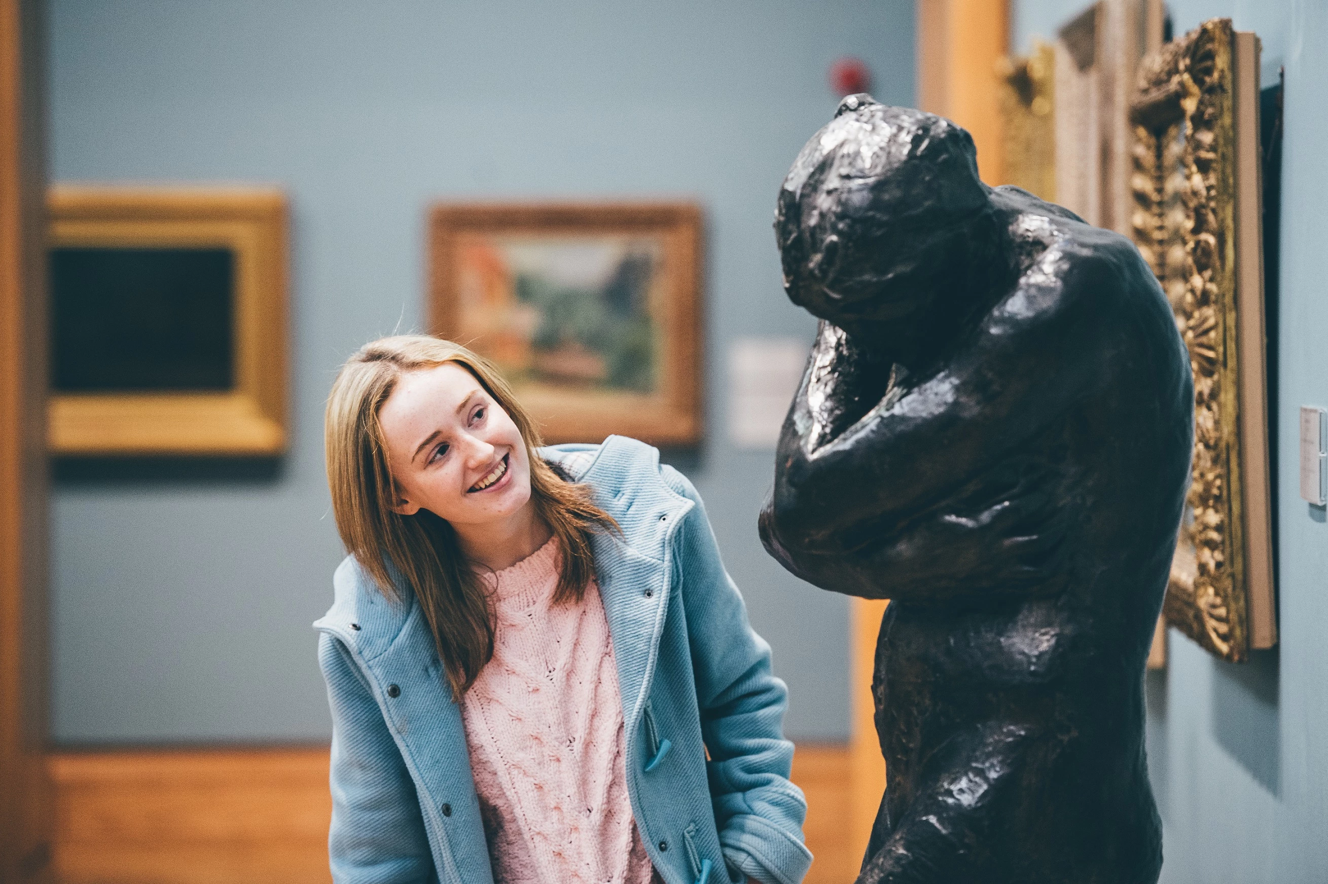 Menyw ifanc yn mwynhau edrych ar gerflun