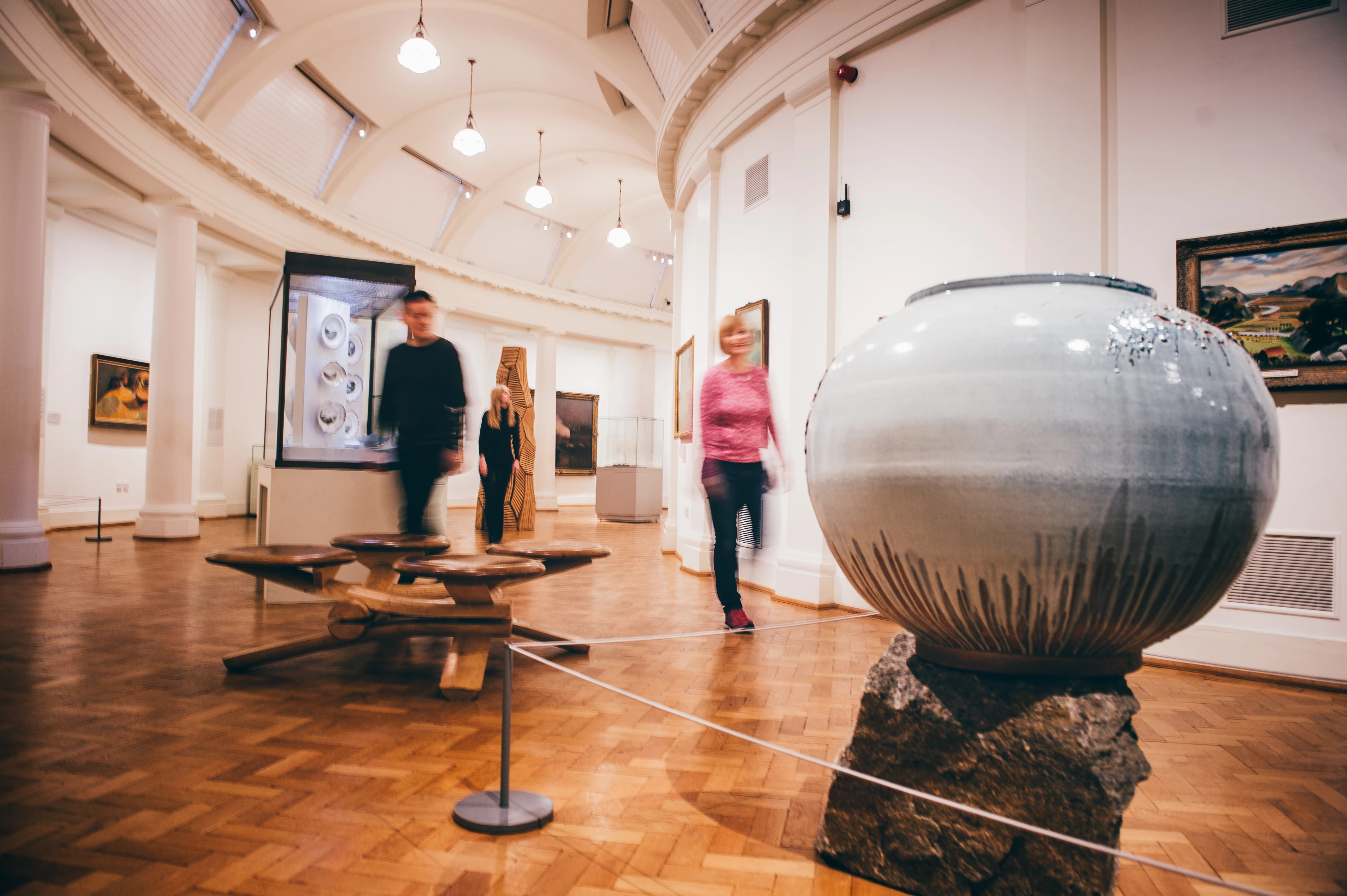 Tri person yn cerdded trwy oriel Tirweddau Cymru