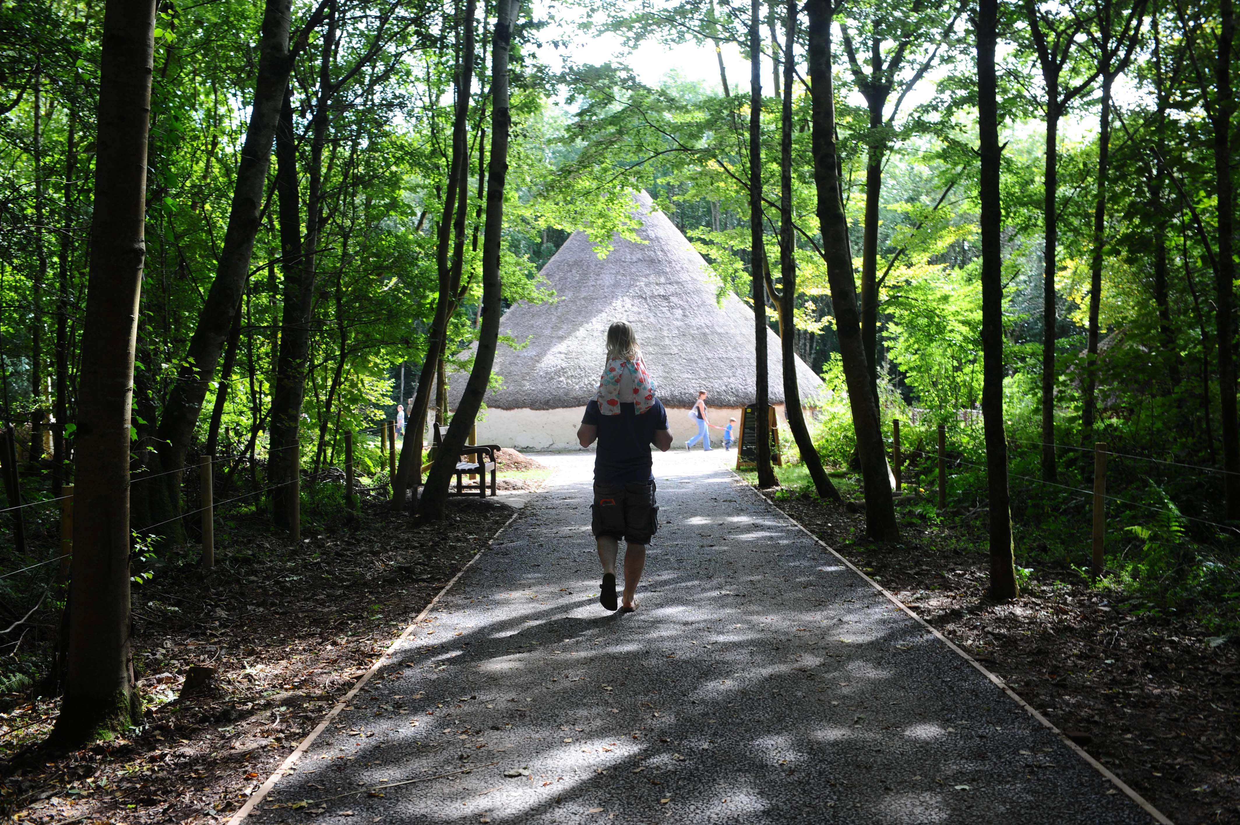 Llun o oedolyn a phlentyn yn cerdded mewn Sain Ffagan