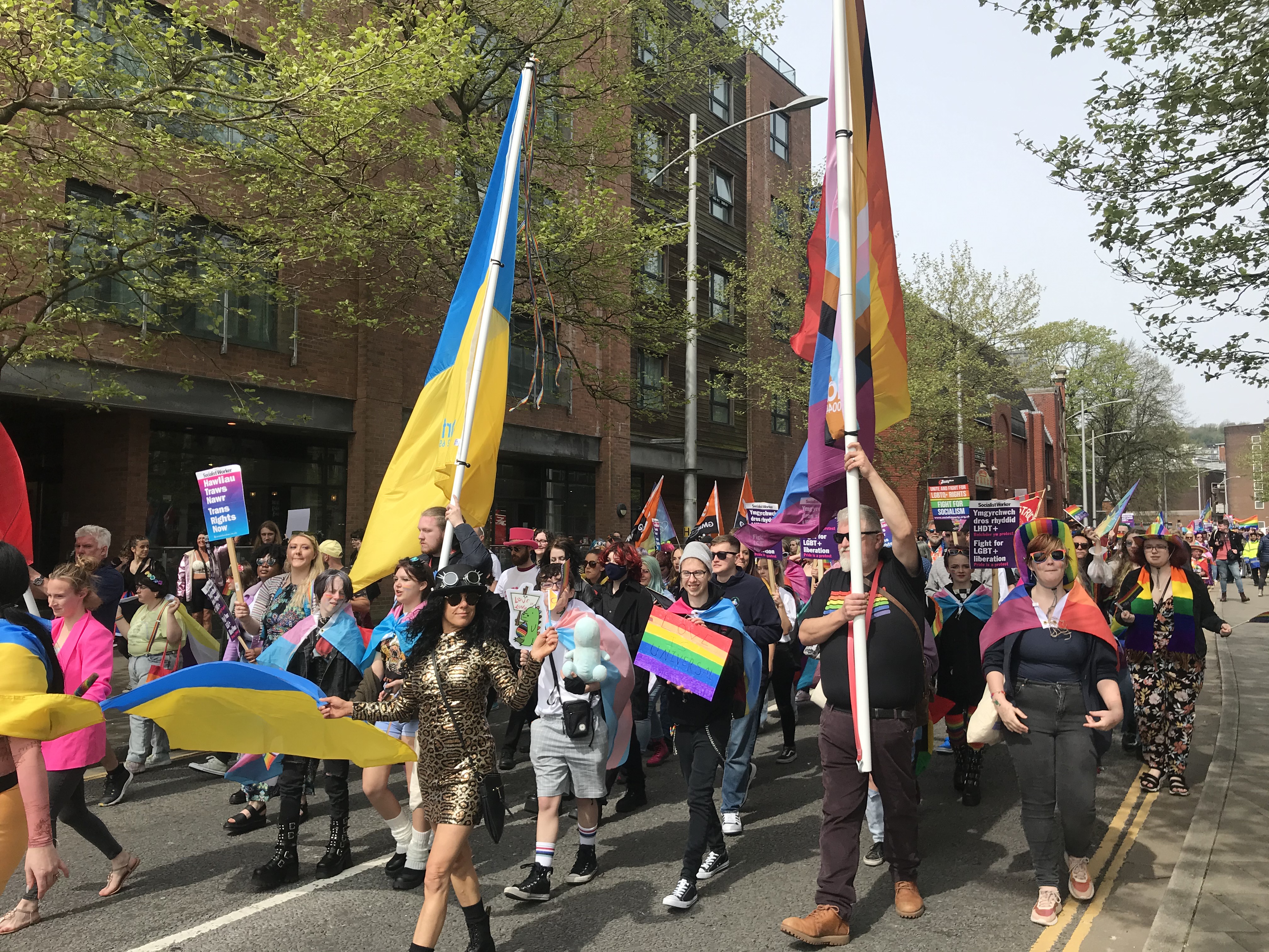 Llun o orymdaith Pride Abertawe gan gynnwys unigolion yn dal banner Wcrain a banner LGBTQ+