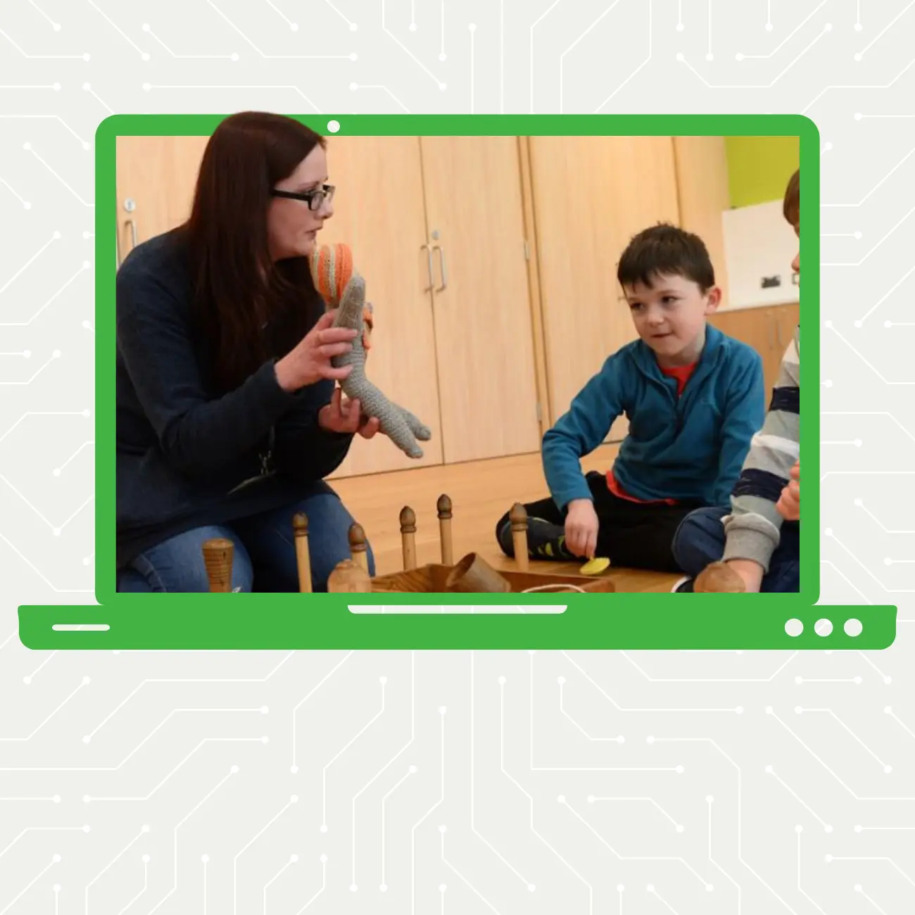 Menyw â gwallt tywyll yn dal cwningen wedi'i stwffio i fachgen yn gwisgo siwmper las