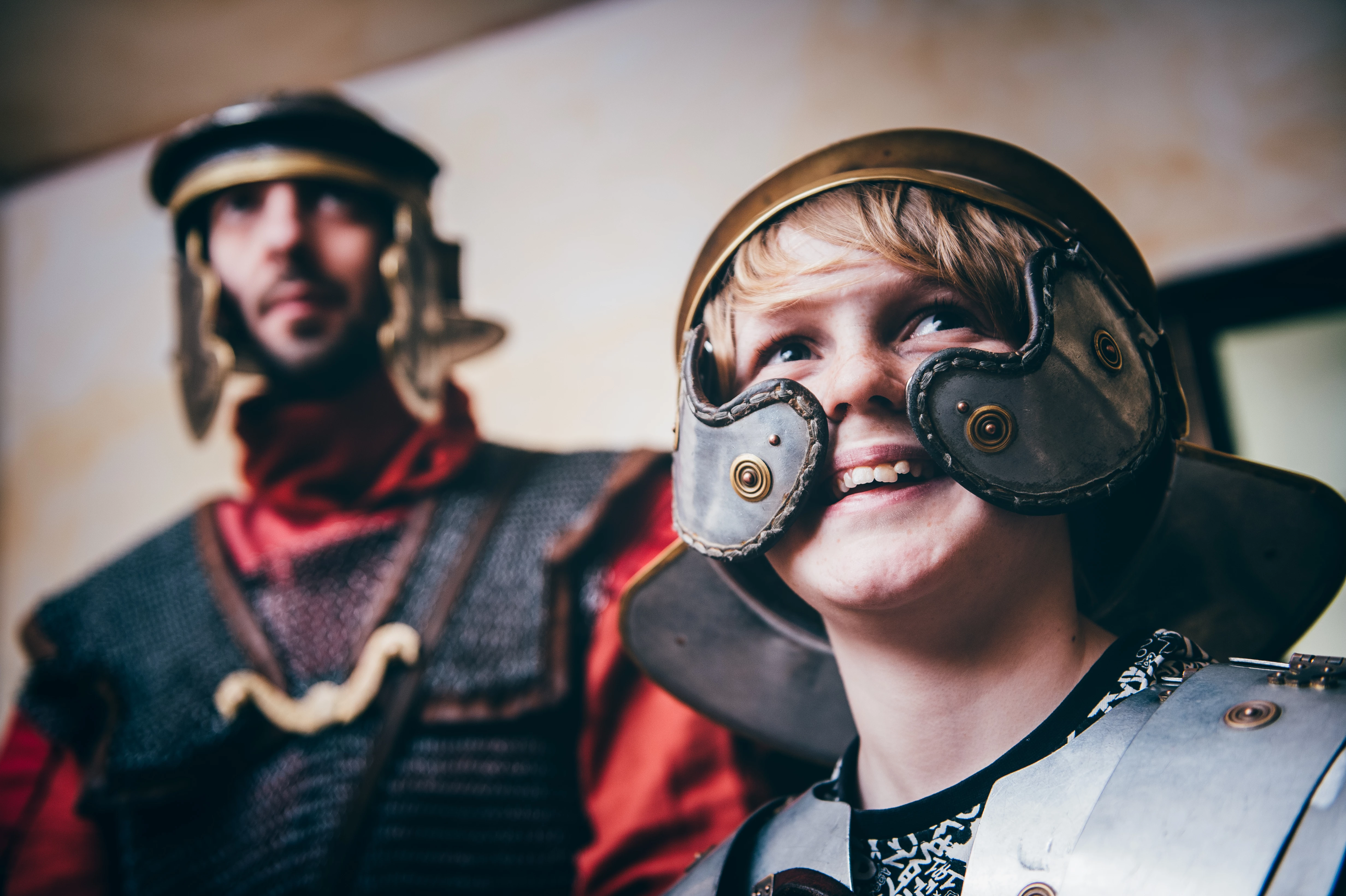 Plant mewn arfwisg Rufeinig yn sefyll y tu ôl i darian.