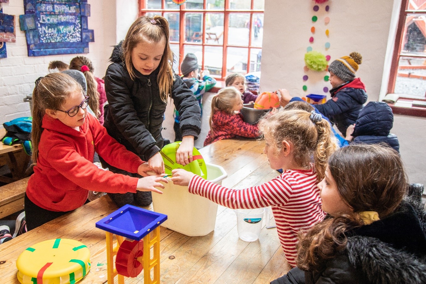 Plant yn cydweithio i adeiladu olwyn ddwr allan o blatiau a chwpanau plastig