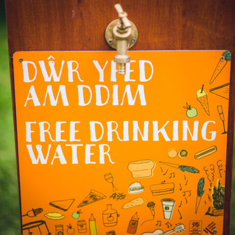Arwydd oren sy'n dweud 'Dwr Yfed am ddim' 'Free drinking water'