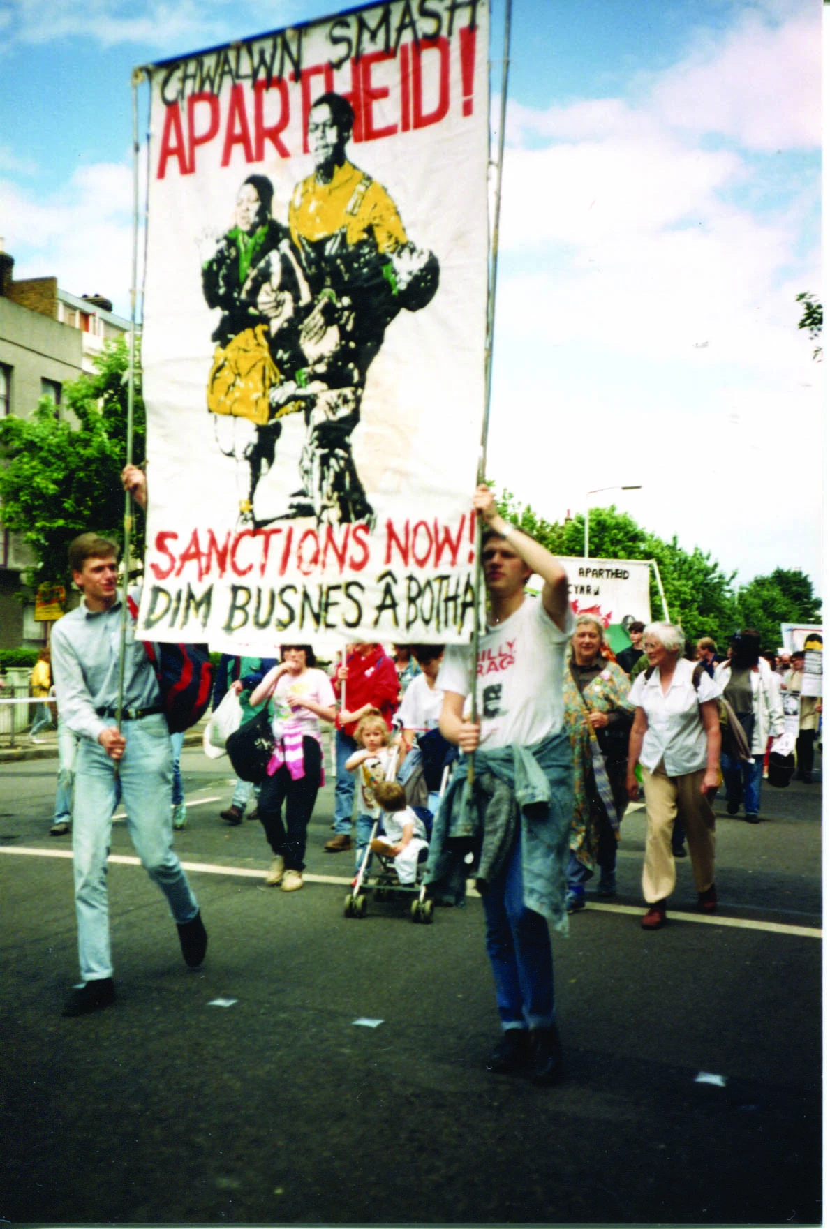 Baner Sanctions Now! mewn protest yn y 1980au