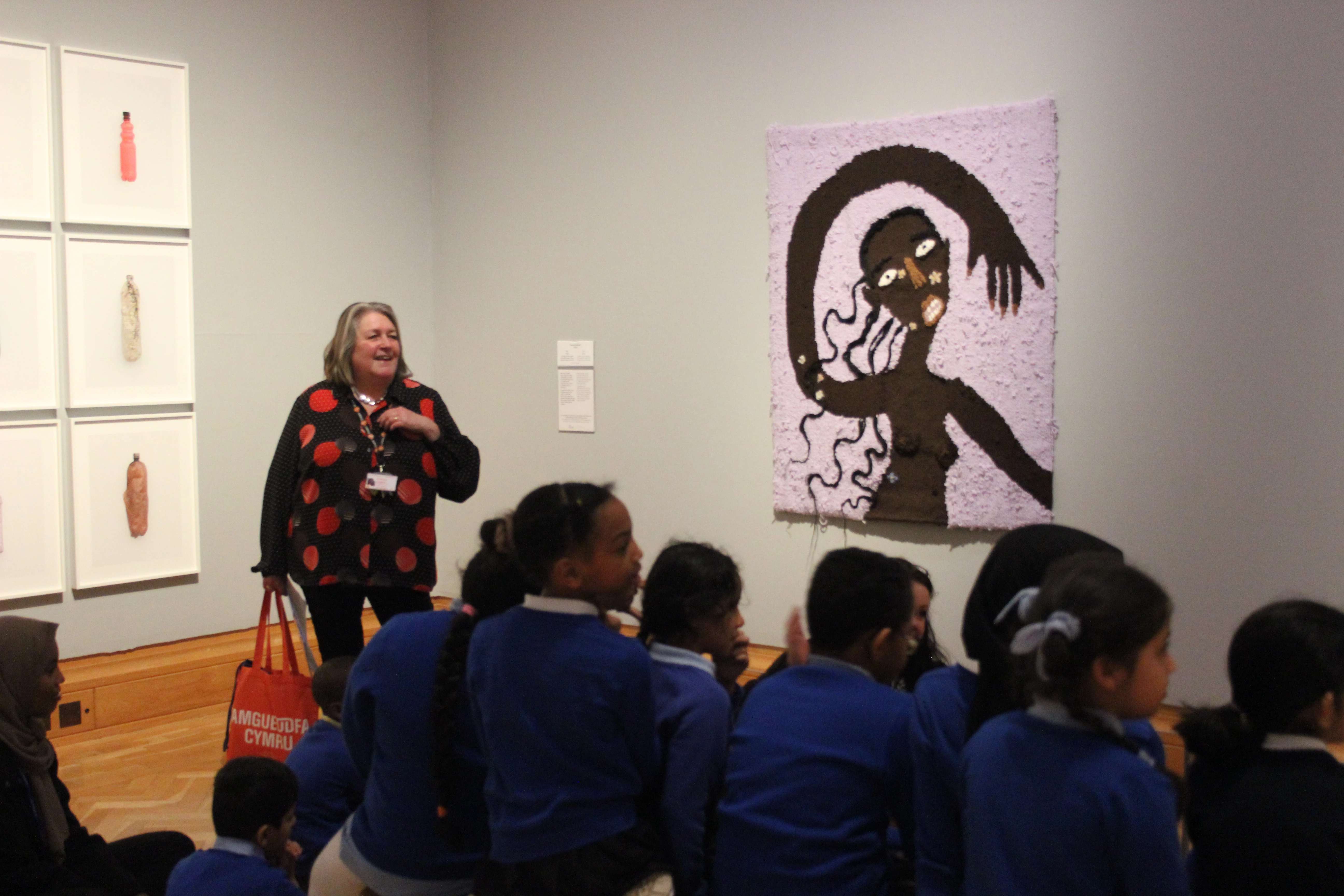 Llun o grŵp o blant ysgol yn edrych ar waith celf yn yr oriel