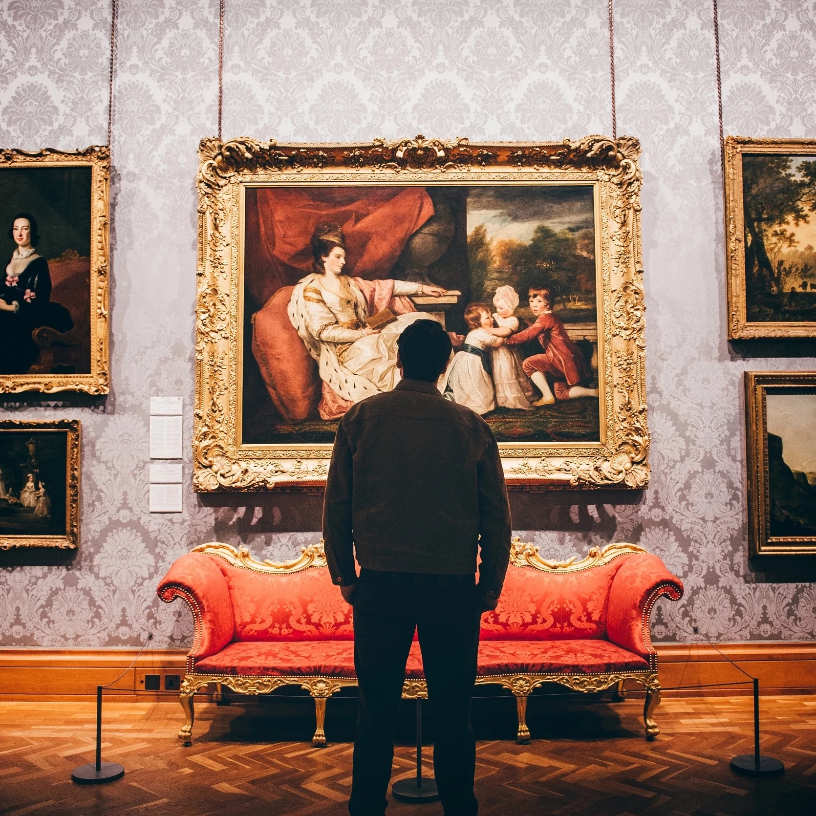 Person yn edrych ar bortread mawreddog o'r ddeunawfed ganrif yn Amgueddfa Genedlaethol Caerdydd