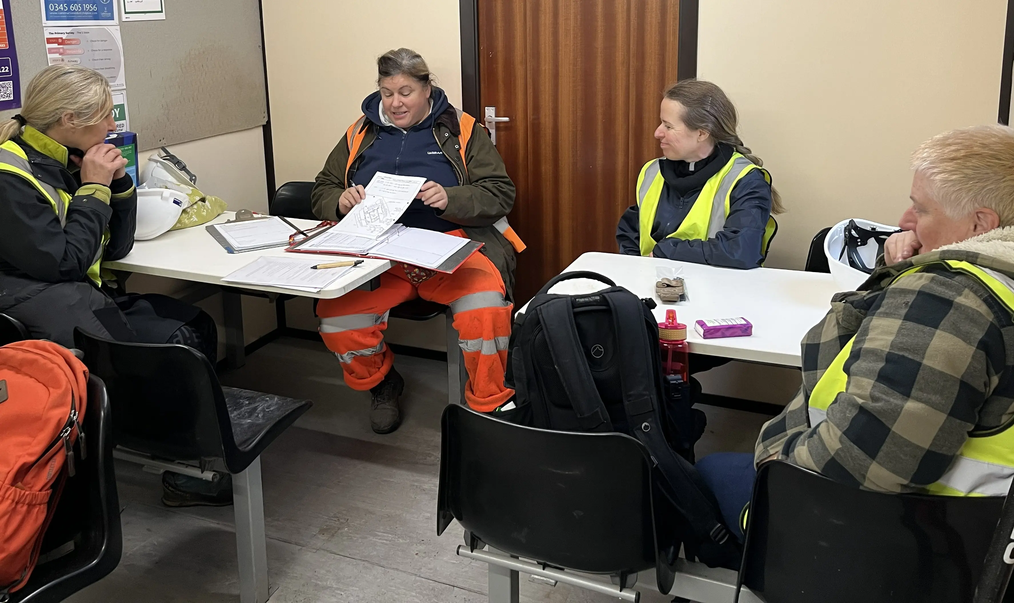 Gwirfoddolwyr yn eistedd o amgylch bwrdd gyda archeolegydd.